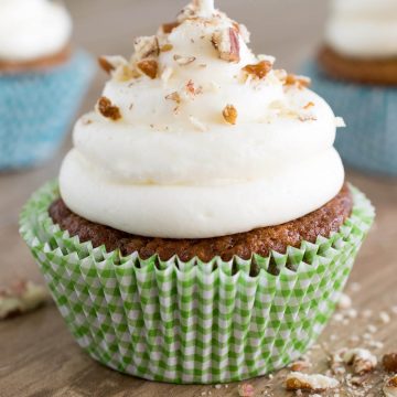 Single carrot cake cupcake with cream cheese frosting piled high.