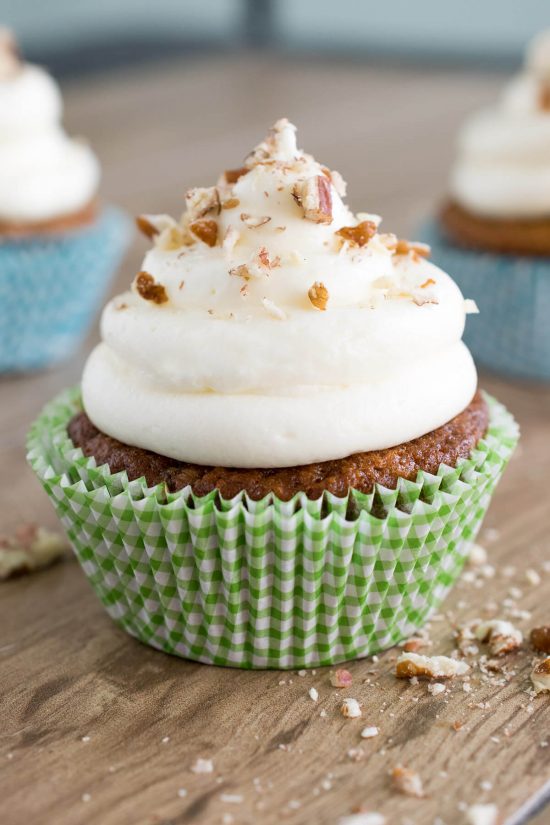 Single carrot cake cupcake with cream cheese frosting piled high.
