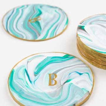 Monogrammed marbled coasters made out of clay and set on a white background.