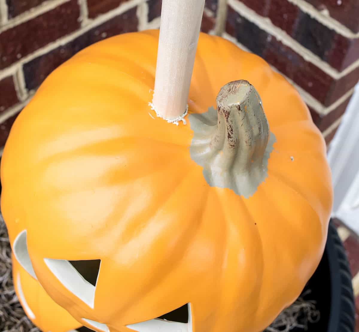 Wooden dowel protruding out of top of carvable pumpkin showing off-center placement. 