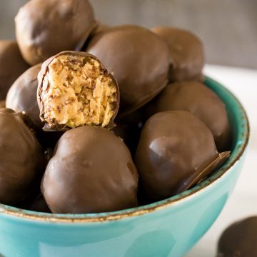 A bowl of peanut butter balls with one bite taken out to show inner texture.
