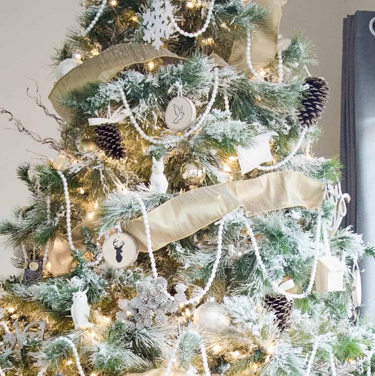 Close up of woodland Christmas tree with gold ribbon, pearl garland, snowflakes and natural elements.