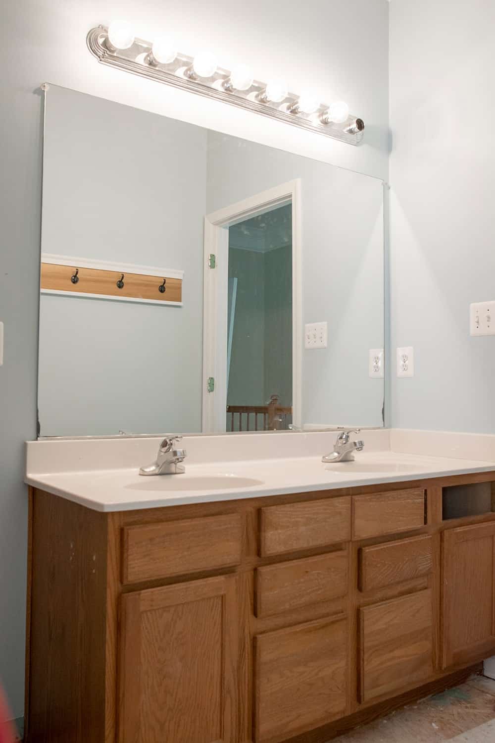 Plain Oak double vanity with no hardware and a single large mirror.