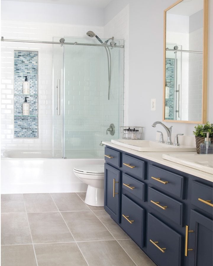 Modern Classic Guest Bathroom Transformation with white and navy color scheme. Subway tile, dual vanity, brass hardware.