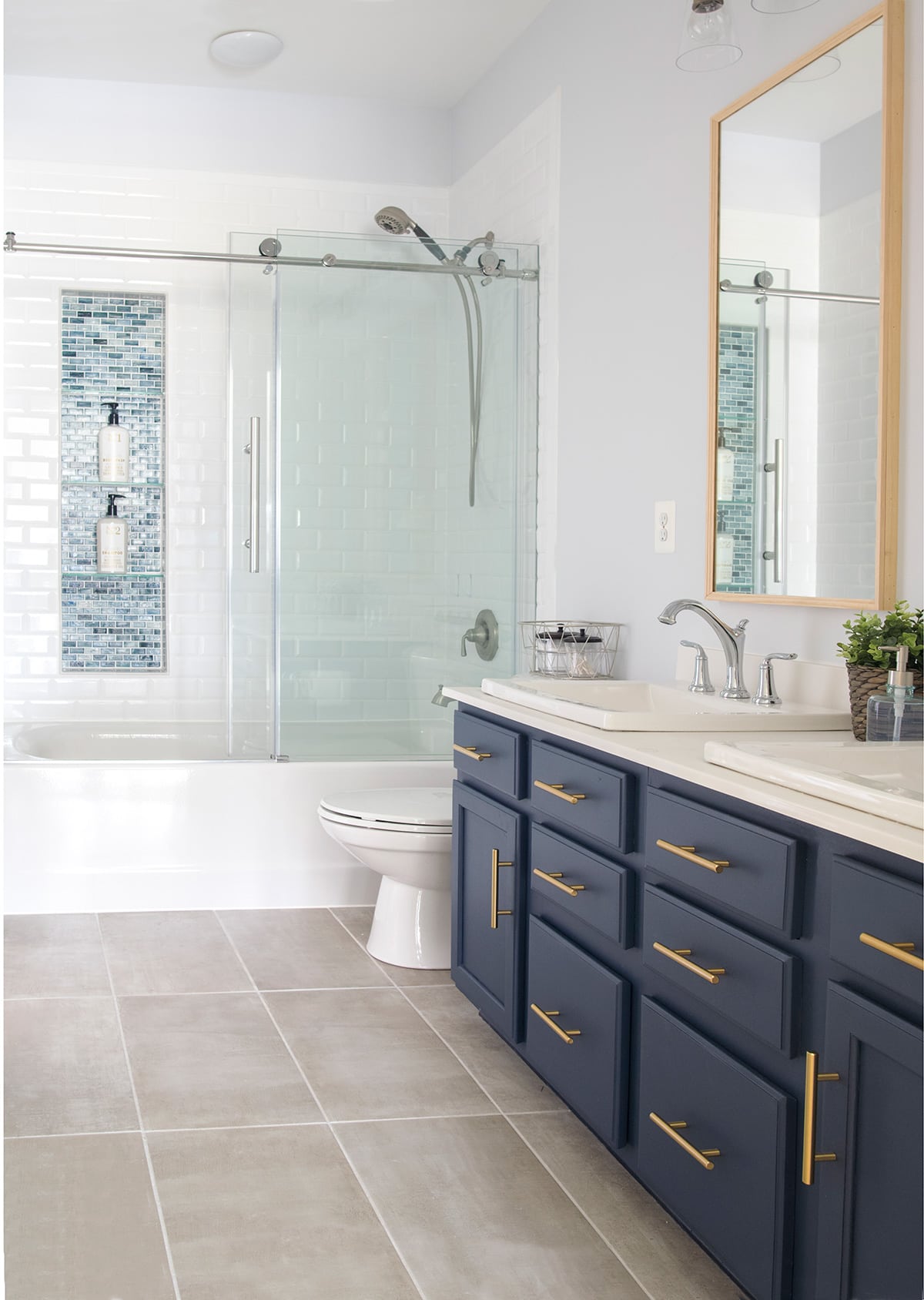 Modern Classic Guest Bathroom Transformation with white and navy color scheme. Subway tile, dual vanity, brass hardware.