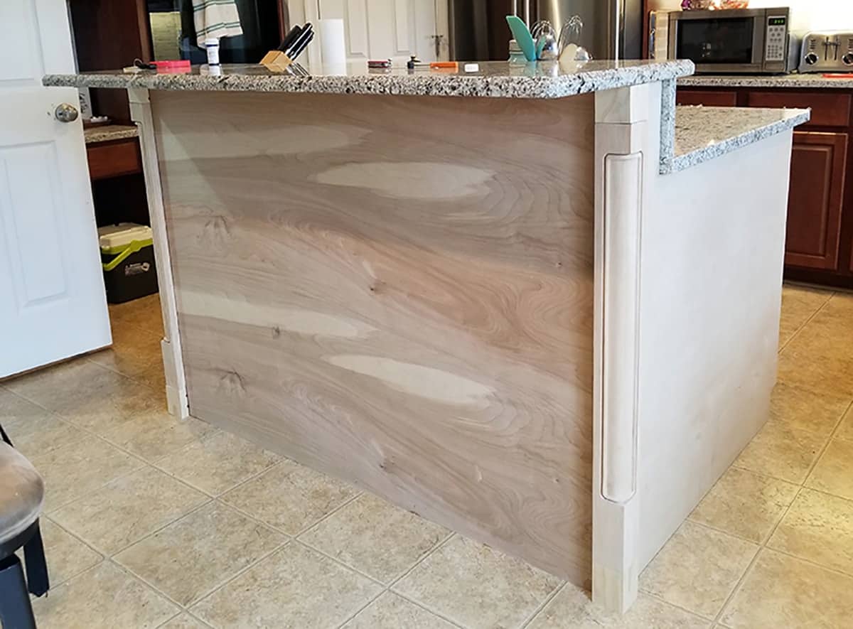 Blank surface wood faced kitchen island with corner posts.