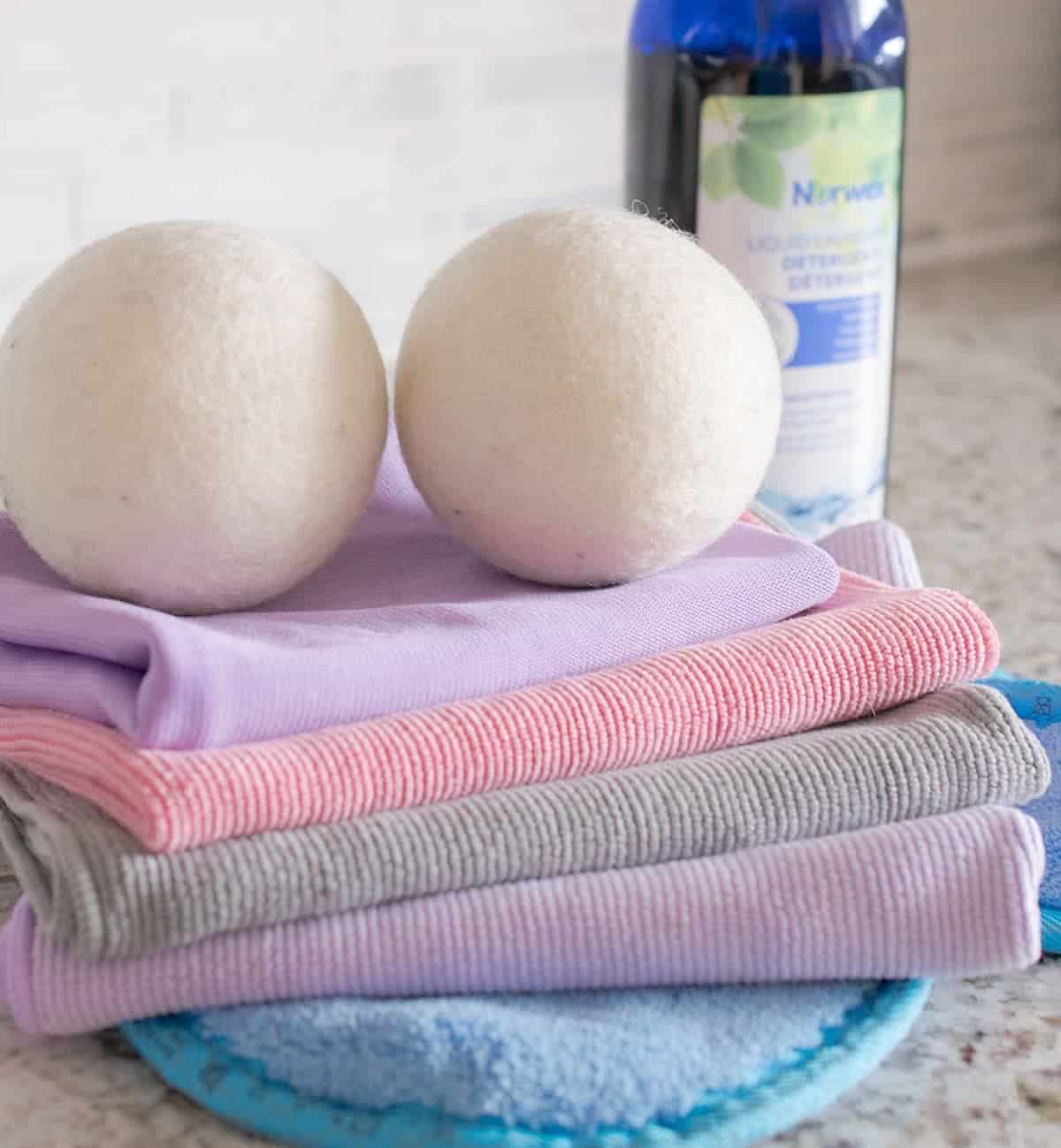 Norwex Enviro Cloth and Window Cloth and two Norwex cleaning balls, solution in background.