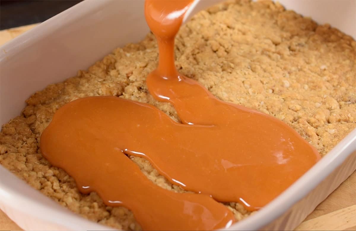 Melted caramel poured over Oatmeal base for Caramalita bars.