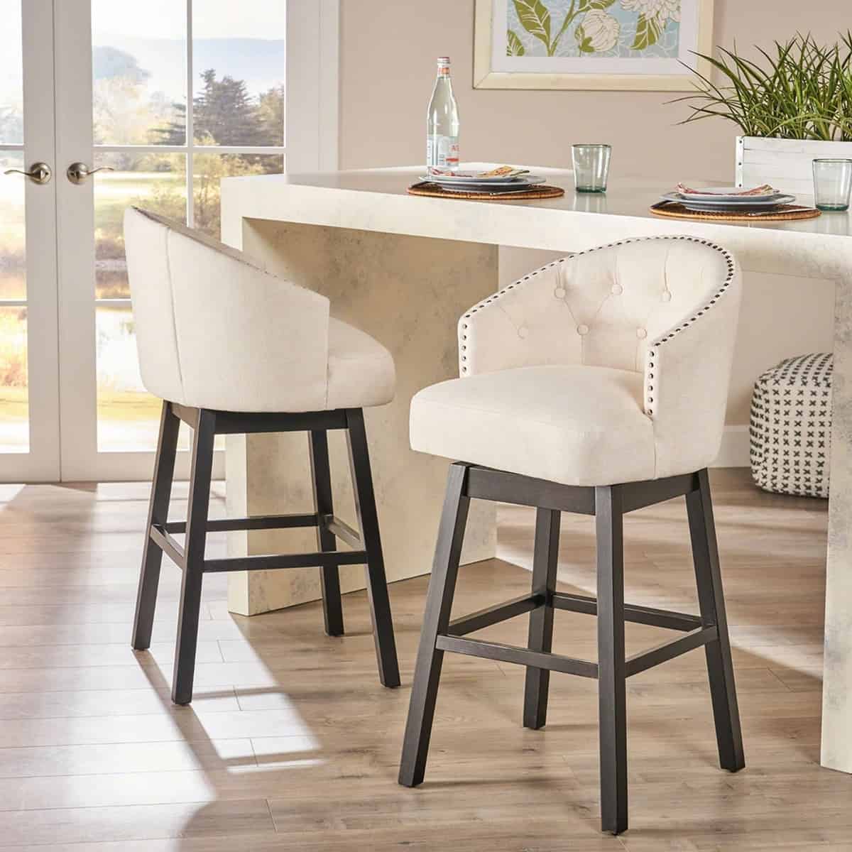 Beige tufted counter stool with beautiful detailing in front of a kitchen counter.