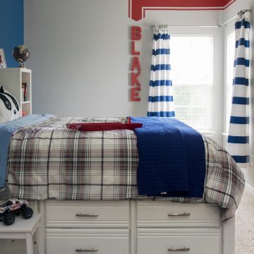 Boys bedroom in grey and navy with red accents and a red racing stripe painted on the wall.
