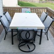 White outdoor table with black chairs on a deck.