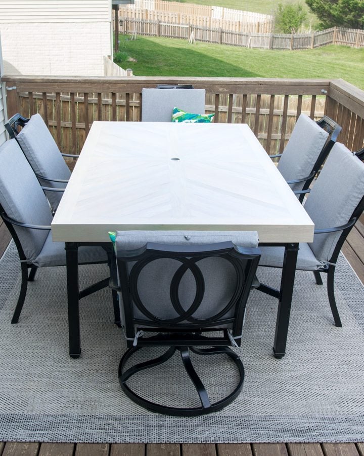 White outdoor table with black chairs on a deck.