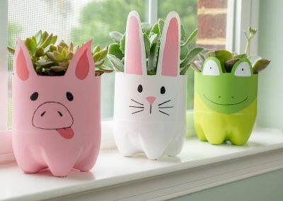 Plastic bottle animal planters on a window sill. Includes a pig, rabbit, and frog planter.