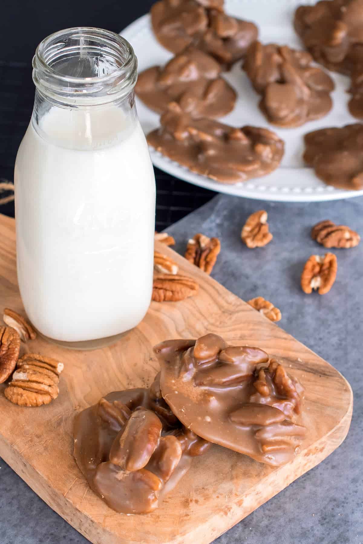 New Orleans Style Pecan Pralines on white plate with mason jar of white milk on cutting board