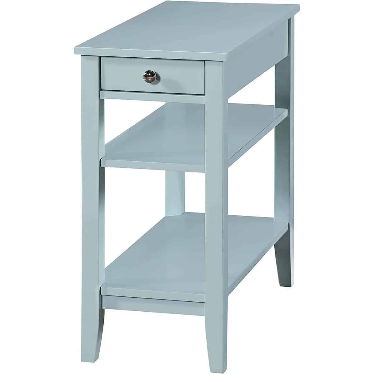 Narrow blue end table on stilted legs with two shelves and a top drawer with round pull.