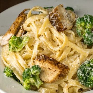 Cajun chicken alfredo pasta in a bowl with parmesan and broccoli on top.