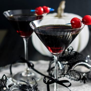 Rum and coke in a martini glass with marchino cherry garnish.