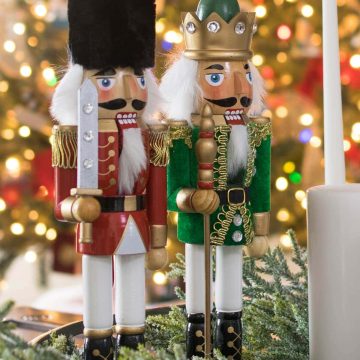 Two nutcracker princes standing in front of a Christmas tree.