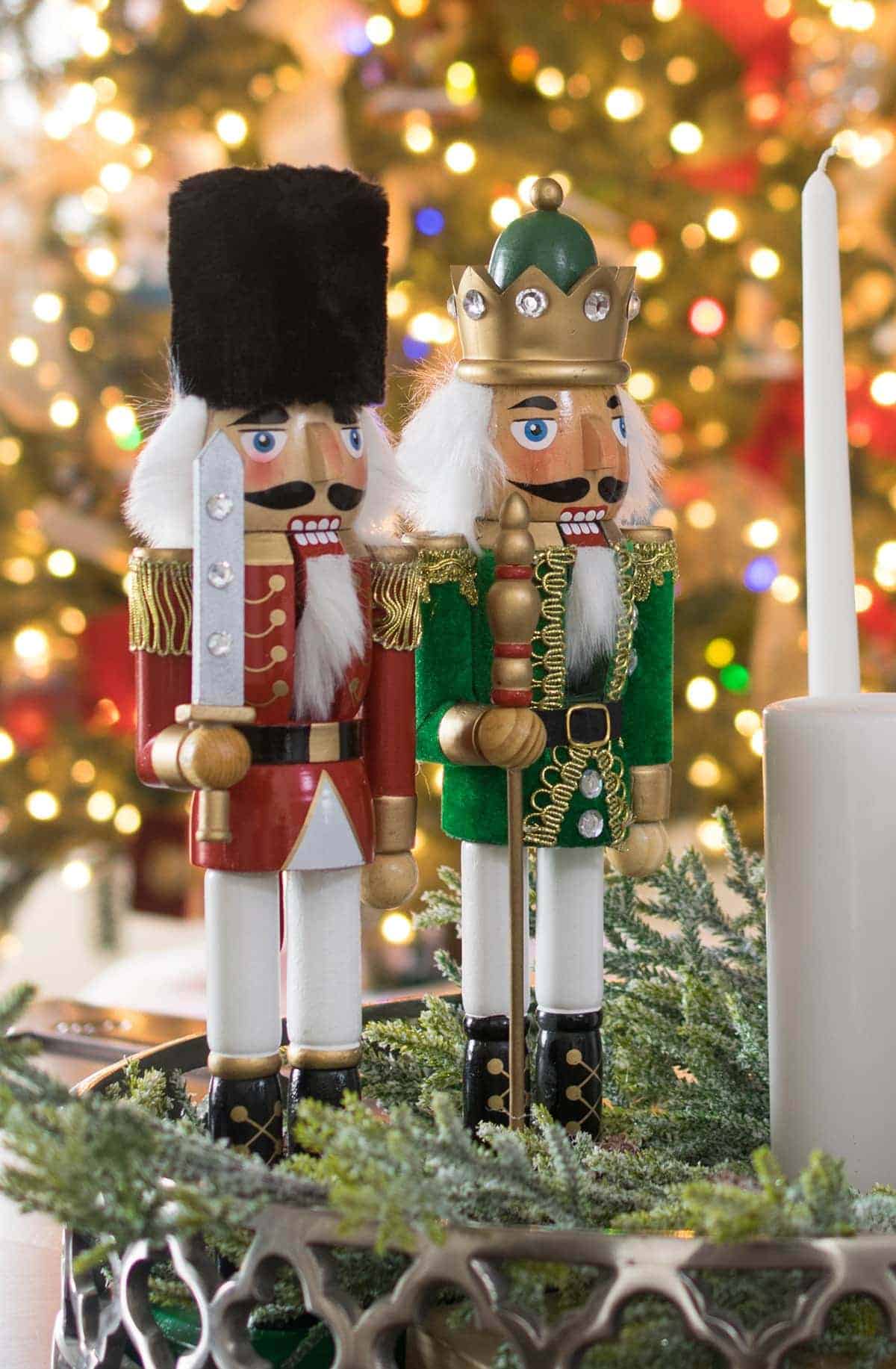 Two nutcracker princes standing in front of a Christmas tree.