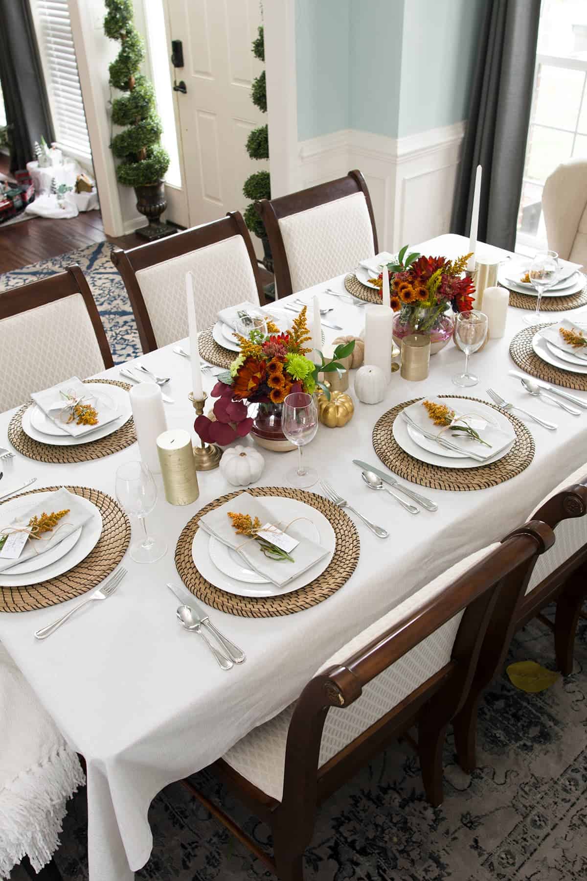 Simple Thanksgving table setting with white and autumn inspired palette, natural elements-overhead view.