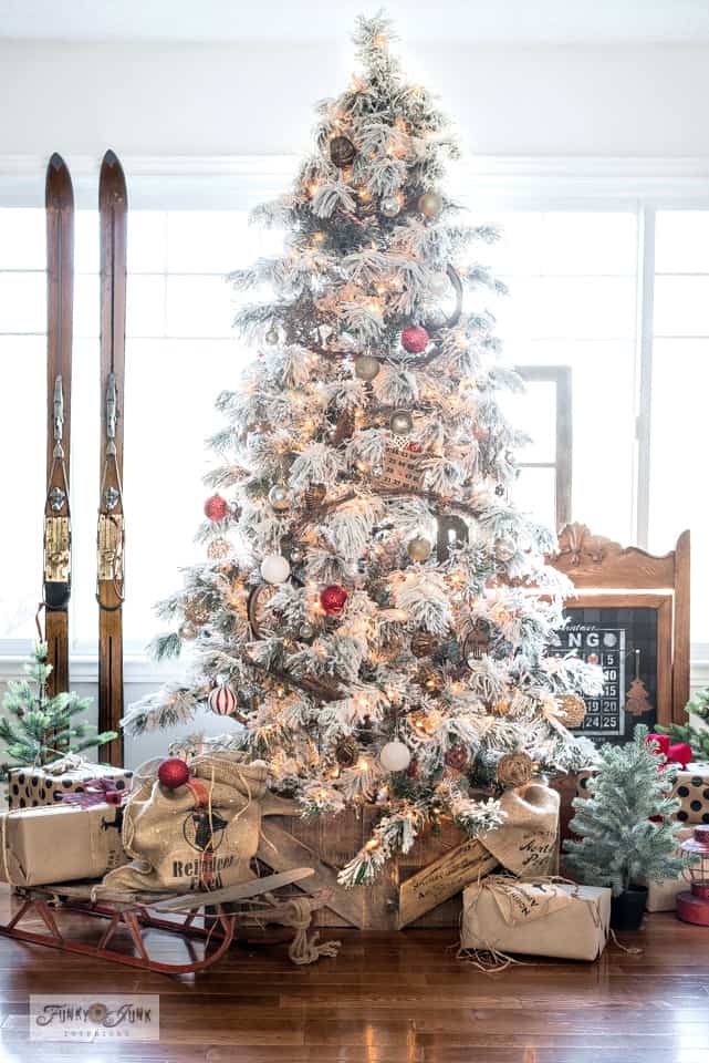 Rustic flocked christmas tree with red ornaments and wooden crates at the bottom.