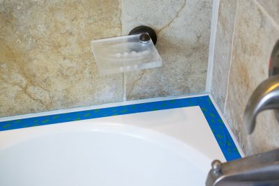 Painter's tape along a bathtub edge in preparation to caulk the edge.
