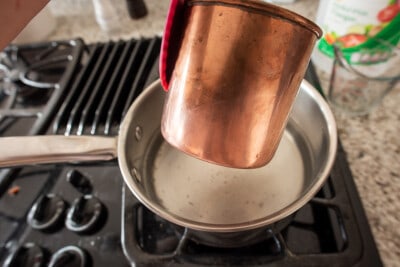 Removing tarnish from copper with half done copper pot over boiling pan.