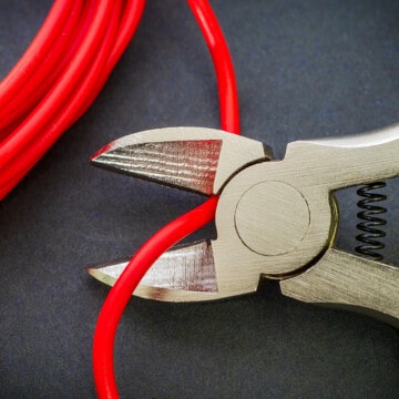 Closeup of cutting through a wire with cutting pliers.