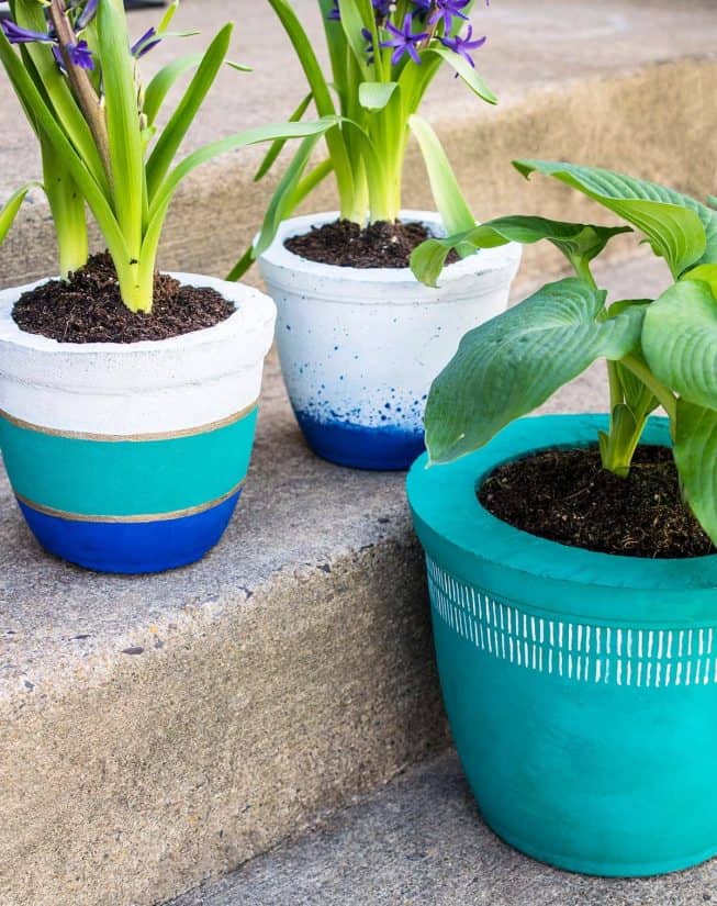 Three colorful planters made of concrete. A DIY project with painted pots.