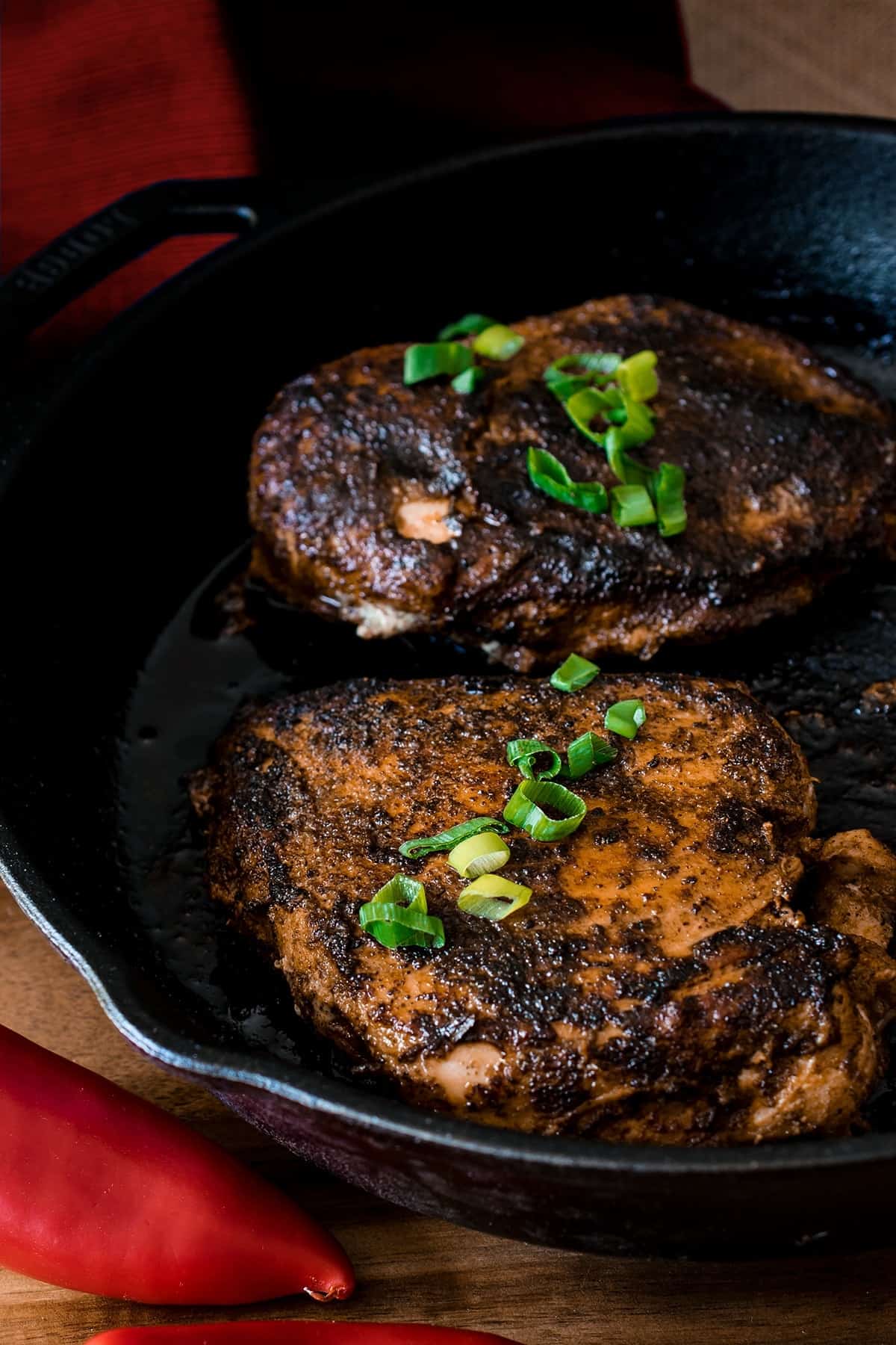 Cajun Blackened Chicken with green onions garnish in a cast iron skillet.