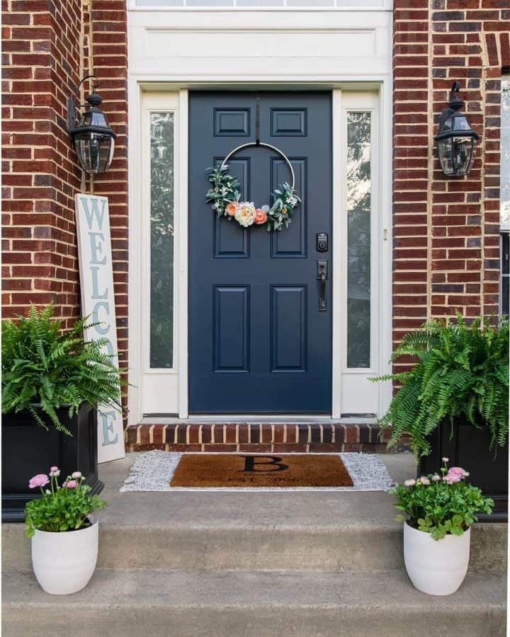 Blue front door on red brick house with planters on either side.