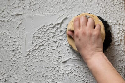 Closeup of hand putting texture on wall with plaster.