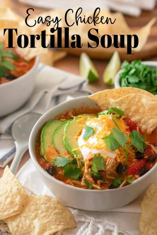 Chicken Tortilla Soup in a bowl topped with sour cream, avocado, cilantro, and cheddar cheese.
