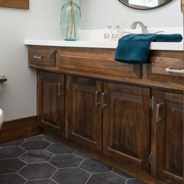 Rustic bathroom with dark wood vanity, black hexagon floors, and white walls.