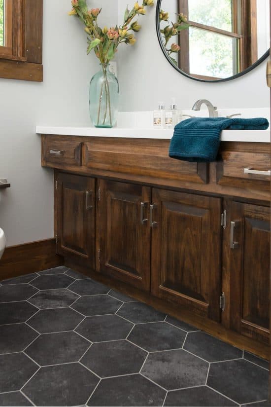 Rustic bathroom with dark wood vanity, black hexagon floors, and white walls.