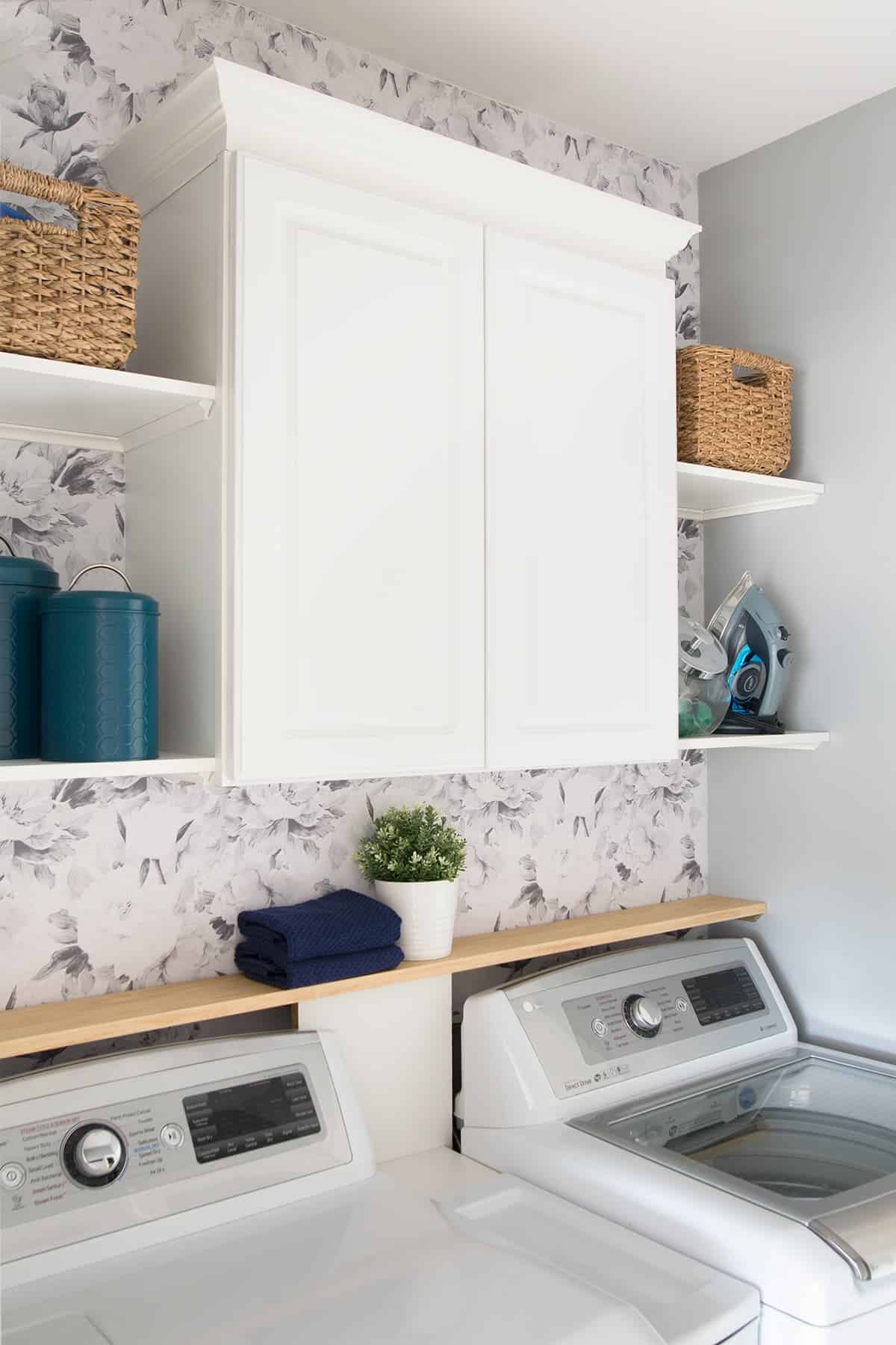 White laundry room with floral wallpaper and teal accents.