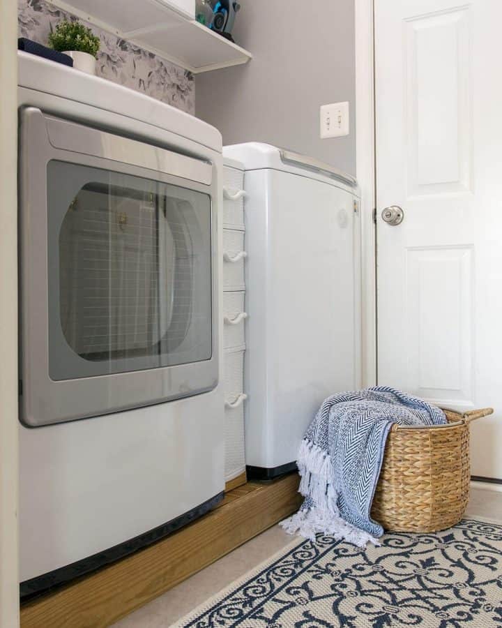 Front of washer and dryer in a small laundry room makeover with gray paint and peel and stick floral wallpaper.