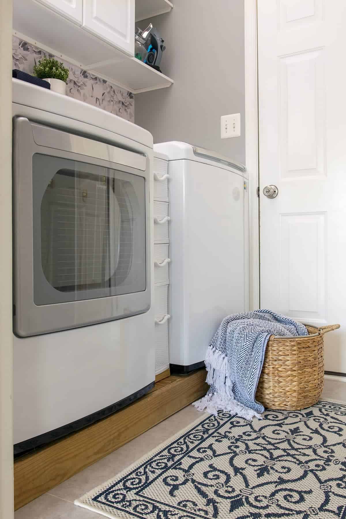 Front of washer and dryer in a small laundry room makeover with  gray paint and  peel and stick floral wallpaper.