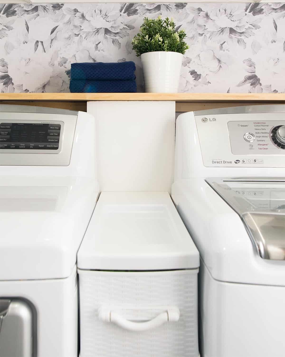 Space between washer and dryer filled with organizing drawers and a shelf.