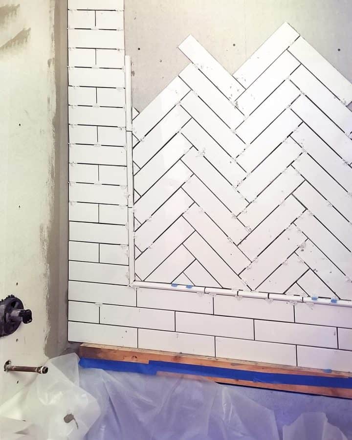 In progress photo of laying herringbone pattern with ceramic tile inset with subway tile surround.