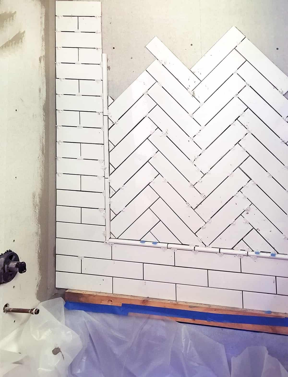 In progress photo of laying herringbone pattern with ceramic tile inset with subway tile surround.