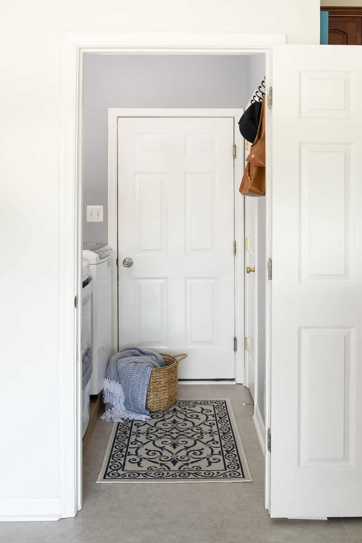 Small laundry room with white door and blue rug.