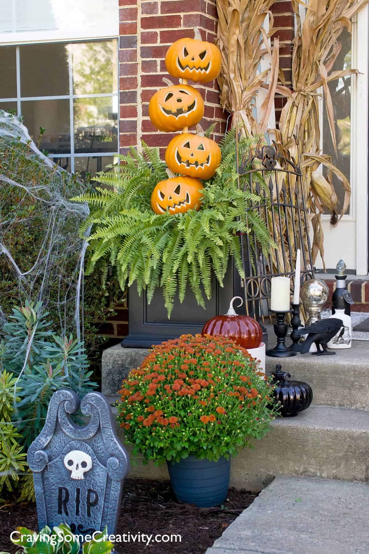 Outdoor Halloween decorations such as a Pumpkin Topiary, spider webs, corn stalks, and witch potion Shoppe décor.