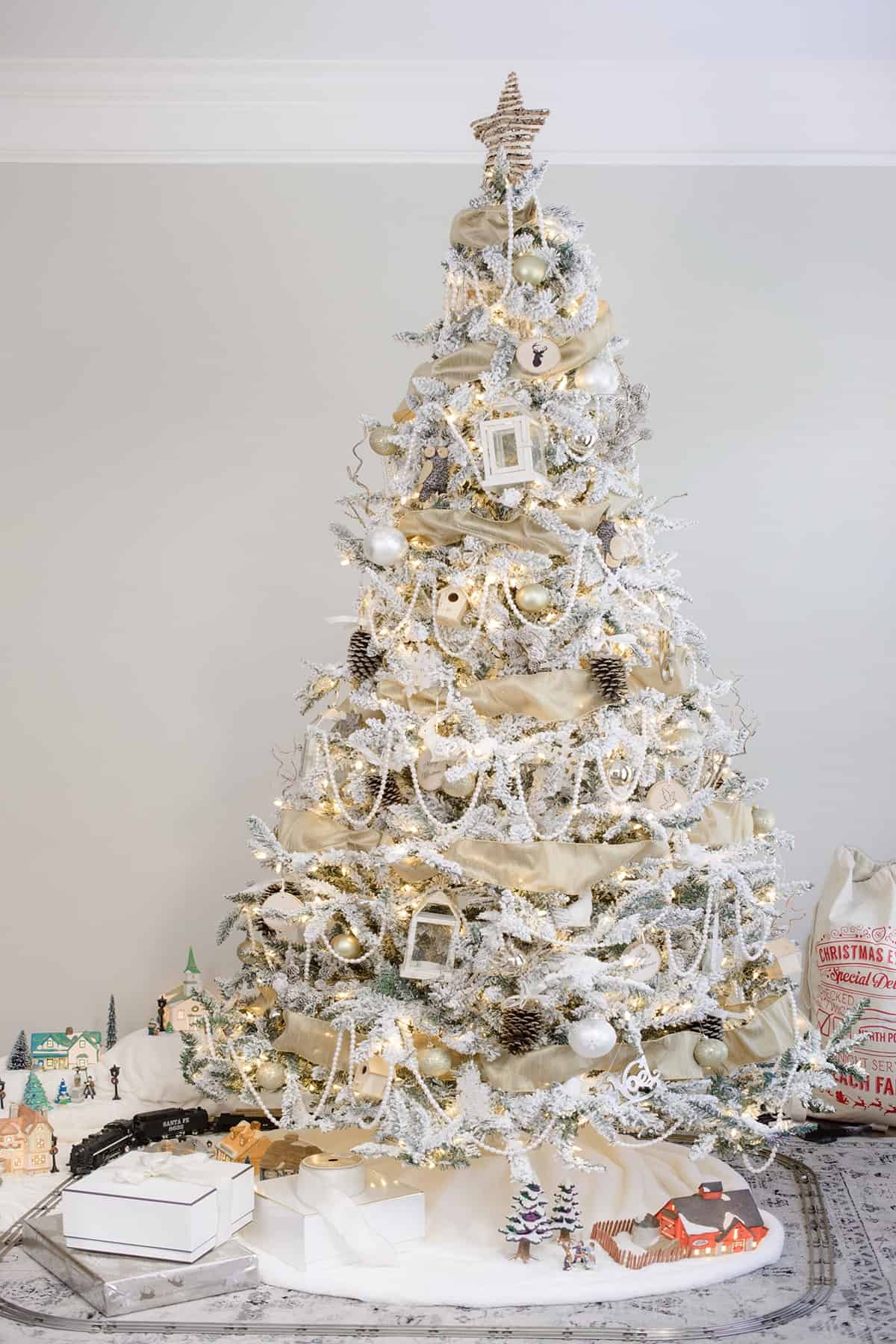 Glam White Woodland Christmas Tree in front room with snowy antique Christmas village and antique train set.