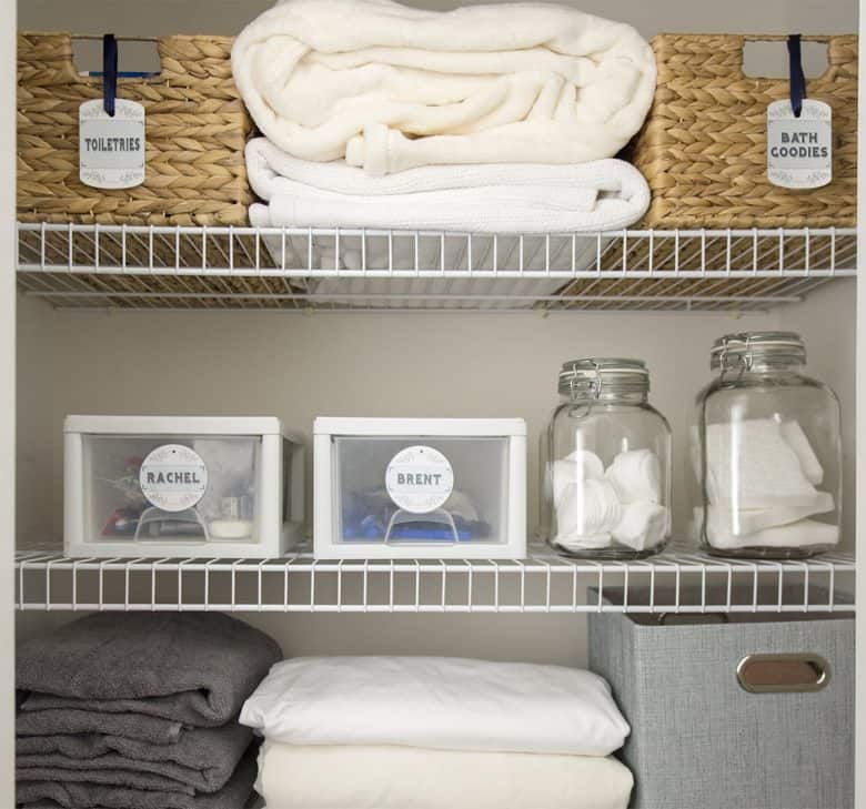 Organized Linen closet with printable labels on baskets and plastic containers. 