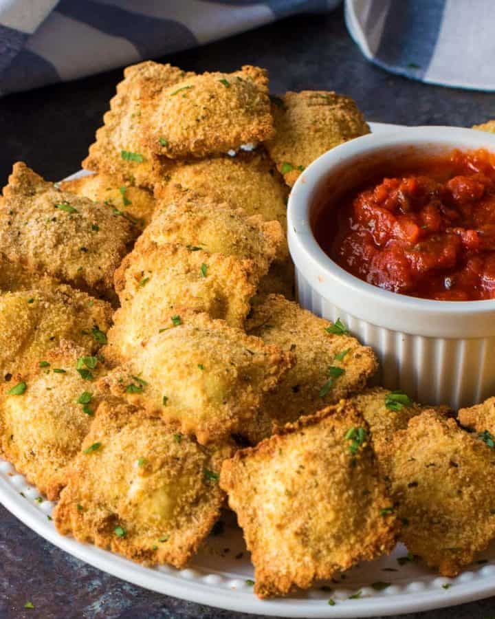 Toasted ravioli rolled in bread crumbs and piled next to marinara dipping sauce for serving.