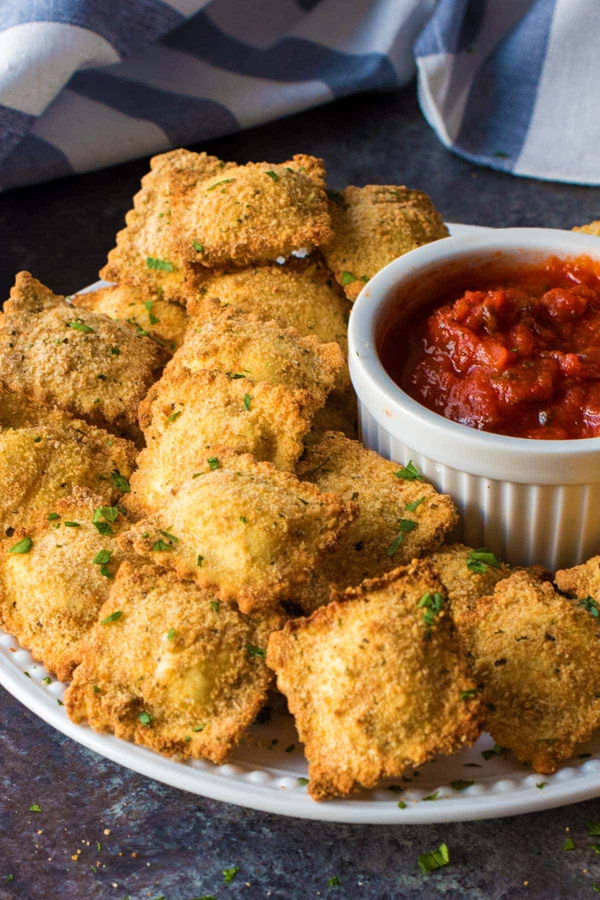 Toasted ravioli rolled in bread crumbs and piled next to marinara dipping sauce for serving.