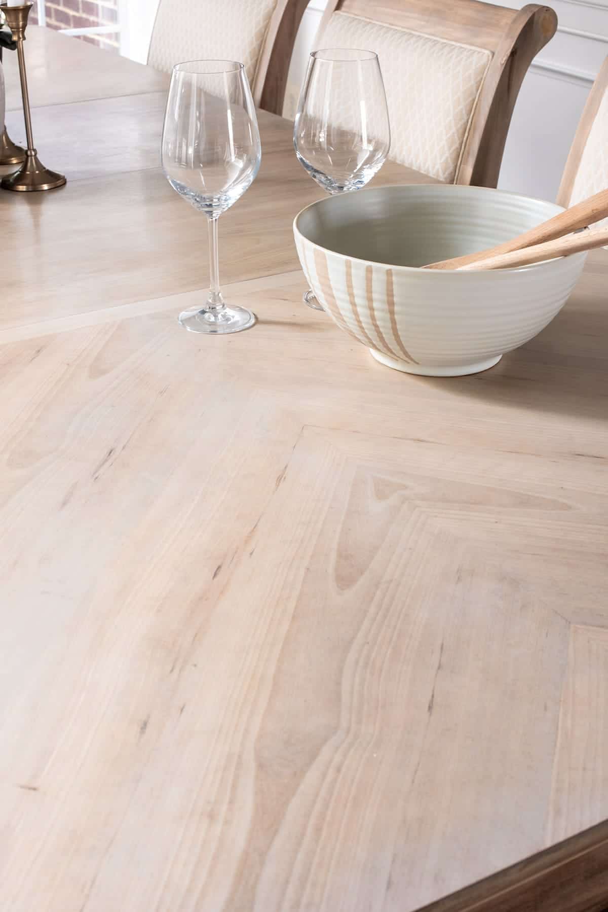 Stripped dining room table after. Wood grain pattern revealed. Wine glasses and white salad bowl with natural accents and wooden utensils for ambiance.