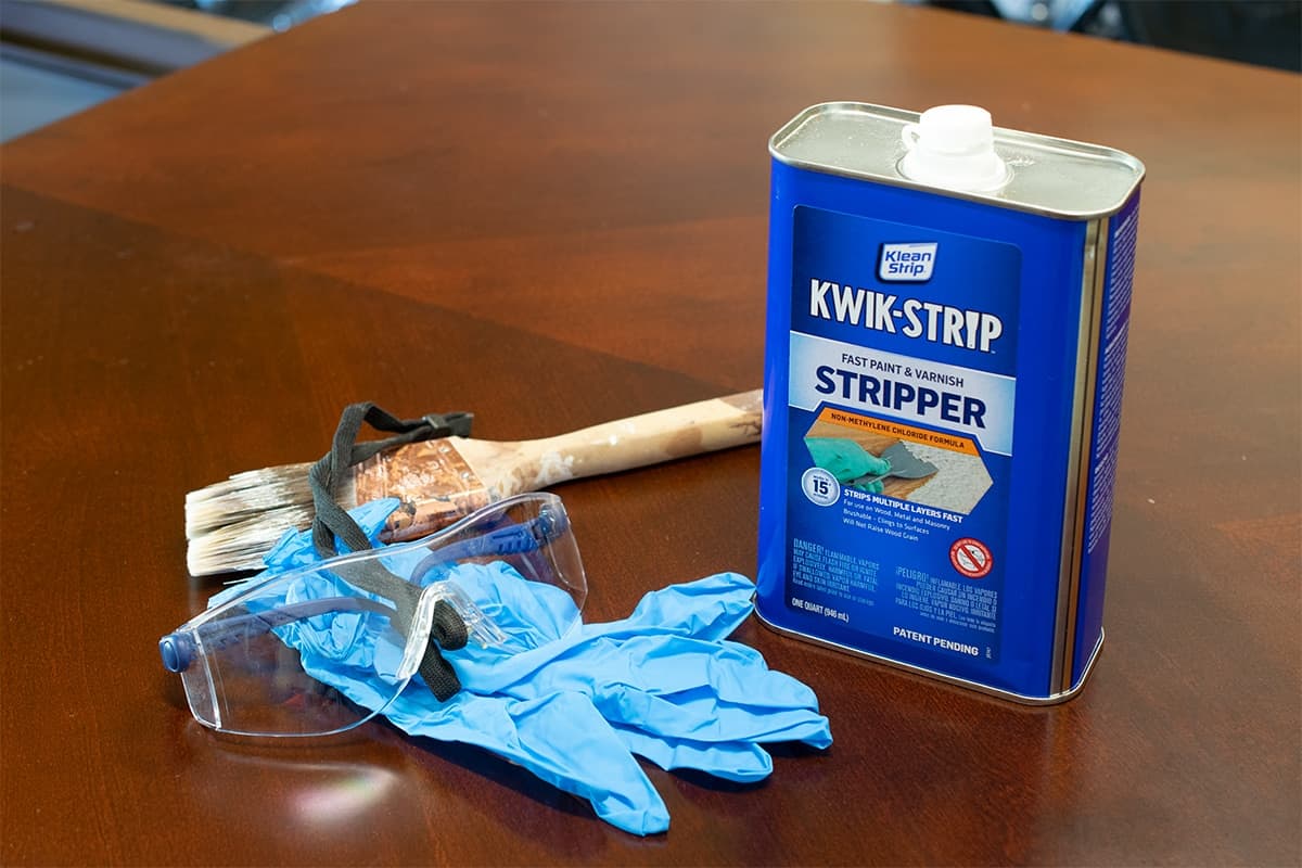 Kwik-strip paint stripper, goggles and gloves sitting atop dining room table in preparation for stripping.