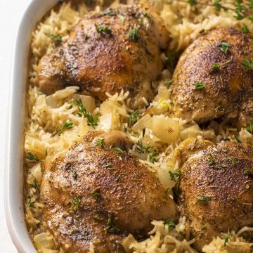 Oven baked chicken and rice in white baking dish.